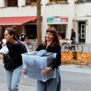 Vielfältiges Produktionsteam der Bridge&Tunnel GmbH Hamburg bei der nachhaltigen Upcycling-Arbeit mit Jeansstoffen in der Textilmanufaktur. Drei Mitarbeiterinnen mit unterschiedlichen kulturellen Hintergründen schneiden und verarbeiten Denim-Materialien zu neuen Designerstücken - ein anschauliches Beispiel für soziale Integration und nachhaltige Modewirtschaft.