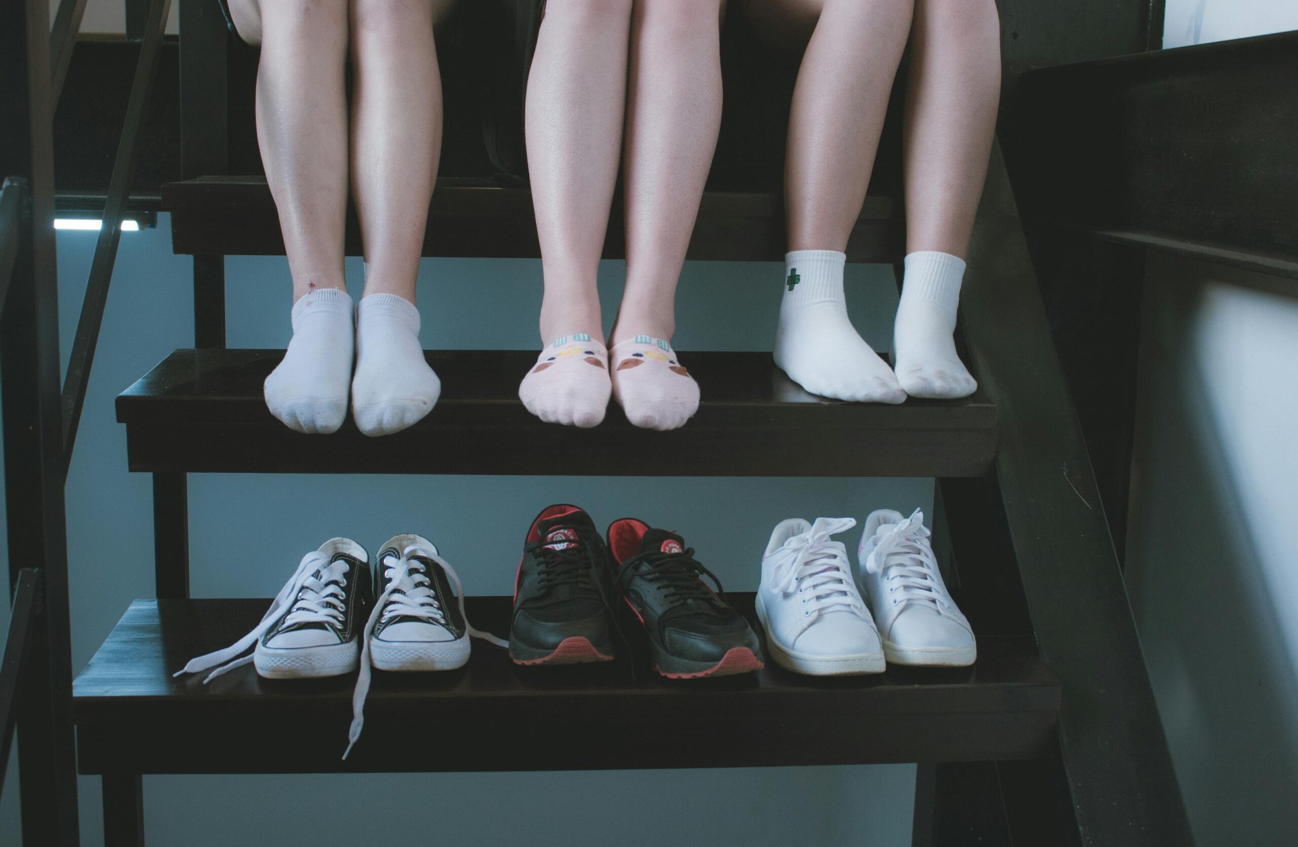Verschiedene nachhaltige Schuhmodelle unter einer Treppe mit drei Personen, die umweltbewusste Alternativen zu konventionellem Schuhwerk präsentieren
